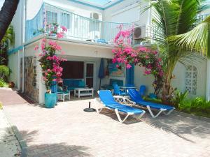 un patio con sillas azules y flores rosas en Villas on Great Bay VILLA FOXIE en Philipsburg