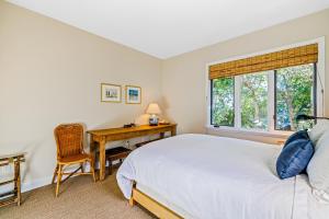 a bedroom with a bed and a desk and a window at Golden Getaway in Summerland