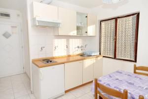 a kitchen with white cabinets and a table and a window at Apartments by the sea Vinisce, Trogir - 5982 in Vinišće