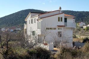 une maison blanche avec une montagne en arrière-plan dans l'établissement Apartments with a parking space Vinisce, Trogir - 5978, à Vinišće