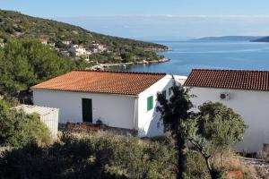 a group of white buildings on a hill next to the water at Apartments by the sea Vinisce, Trogir - 5981 in Vinišće