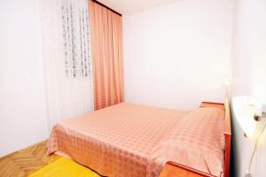 ein kleines Schlafzimmer mit einem Bett mit einer orangefarbenen Decke in der Unterkunft Apartments by the sea Vinisce, Trogir - 5981 in Vinišće
