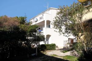 a white building with trees in front of it at Apartment Baska Voda 6057c in Baška Voda