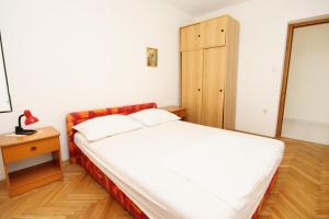 a bedroom with a large bed and a wooden cabinet at Apartment Baska Voda 6057c in Baška Voda