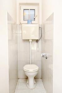 a white bathroom with a toilet and a window at Apartment Baska Voda 6057c in Baška Voda