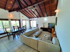 a living room with a couch and a dining room at 3Suítes, piscina e vista do mar em condomínio pé na areia - pátio compartilhado in Búzios