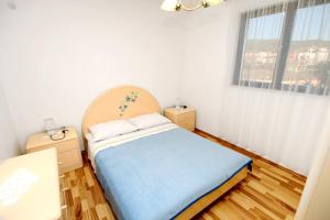 a small bedroom with a bed and a window at Apartments by the sea Vinisce, Trogir - 6015 in Vinišće