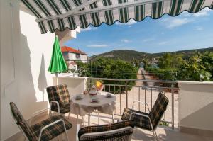 a balcony with a table and chairs and a view at Apartments by the sea Vinisce, Trogir - 6015 in Vinišće