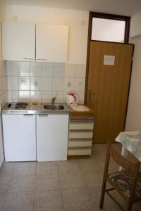 ロクヴァ・ロゴズニツァにあるApartments by the sea Lokva Rogoznica, Omis - 6005の白いキャビネット、シンク、ドア付きのキッチン