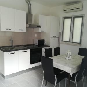 a kitchen with white cabinets and a table with chairs at Apartments with a parking space Seget Vranjica, Trogir - 5966 in Seget Vranjica