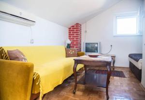 a living room with a yellow couch and a table at Apartments with a parking space Postira, Brac - 6049 in Postira