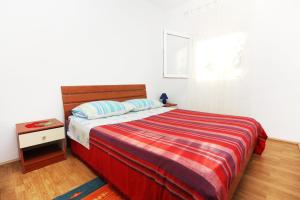 ein Schlafzimmer mit einem Bett mit einer roten und gestreiften Decke in der Unterkunft Seaside holiday house Bibinje, Zadar - 5854 in Bibinje