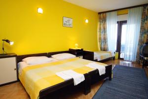 - une chambre avec 2 lits et un mur jaune dans l'établissement Apartments by the sea Lokva Rogoznica, Omis - 6004, à Lokva Rogoznica
