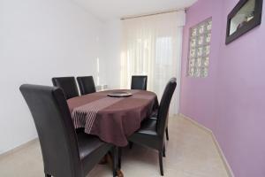 a dining room table with black chairs and a purple wall at Apartments with a parking space Omis - 5988 in Omiš