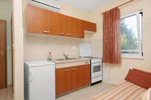 een keuken met houten kasten en een witte koelkast bij Apartments with a parking space Slatine, Ciovo - 5999 in Slatine