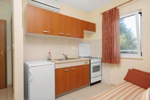a kitchen with wooden cabinets and a white refrigerator at Apartments with parking space Slatine, Ciovo - 5999 in Slatine