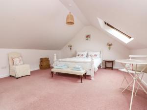 Saint Martins GreenにあるBolitho's Retreatの白いベッドと椅子が備わる屋根裏部屋です。