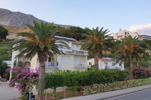 a building with palm trees in front of a street at Apartments by the sea Duce, Omis - 5987 in Duće