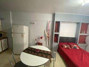 Kleines Zimmer mit einem Bett, einem Tisch und einem Kühlschrank. in der Unterkunft MONOAMBIENTE CENTRICO AMOBLADO in San Juan
