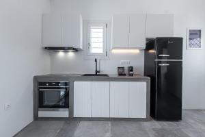 een keuken met witte kasten en een zwarte koelkast bij Manesis Suites in Pollonia