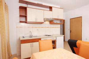 cocina con armarios blancos, fregadero y mesa en Seaside apartments with a swimming pool Nin, Zadar - 5930, en Nin