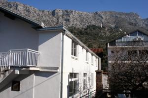 a white building with a balcony in front of a mountain at Apartments with a parking space Podaca, Makarska - 6050 in Podaca