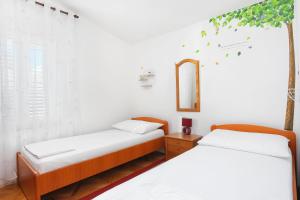 two beds in a room with a mirror and a window at Apartments by the sea Seget Vranjica, Trogir - 6094 in Seget Vranjica
