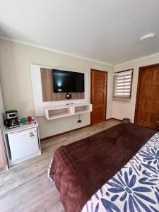 1 dormitorio con 1 cama y TV de pantalla plana en Hotel Boutique Family Suites, en Panguipulli