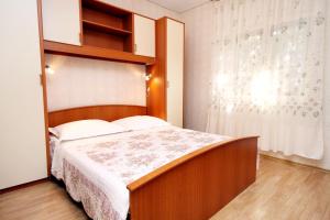 1 dormitorio con 1 cama con cabecero de madera y ventana en Apartments by the sea Arbanija, Ciovo - 6062, en Trogir