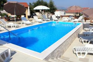 a large swimming pool with chairs and umbrellas at Seaside apartments with a swimming pool Posedarje, Novigrad - 6162 in Posedarje