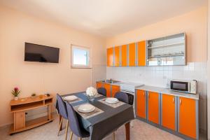una cocina con armarios naranjas y una mesa con sillas. en Seaside apartments with a swimming pool Posedarje, Novigrad - 6162, en Posedarje