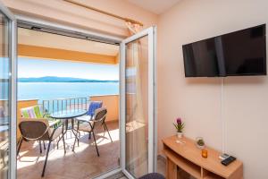 a room with a balcony with a table and a television at Seaside apartments with a swimming pool Posedarje, Novigrad - 6162 in Posedarje