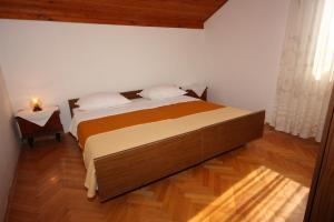 a bed in a bedroom with a wooden floor at Apartments with a parking space Grebastica, Sibenik - 6103 in Grebaštica