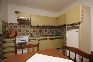 a kitchen with yellow cabinets and a wooden table at Apartments by the sea Tisno, Murter - 6106 in Tisno