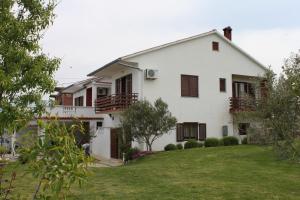 ein weißes Haus mit braunen Fensterläden und einem Hof in der Unterkunft Apartments with a parking space Ljubac, Zadar - 6141 in Ražanac