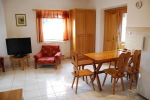 uma cozinha com uma mesa e cadeiras e uma televisão em Boróka Apartmanházak - Fagyöngy House em Velem
