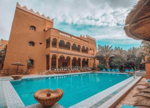 廷吉尔Hotel Kasbah Lamrani的建筑物前的游泳池