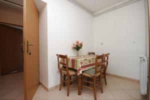 a dining room table with chairs and a vase of flowers at Apartments by the sea Duga Luka - Prtlog, Labin - 7491 in Labin