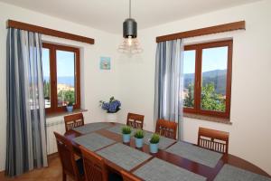 a dining room with a table and chairs and windows at Apartment Rabac 7429a in Rabac