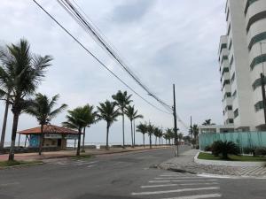Una calle vacía con palmeras y un edificio. en Apartamento beira mar - Mongaguá, en Mongaguá
