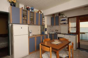 uma cozinha com armários azuis e uma mesa com cadeiras em Apartments by the sea Seget Vranjica, Trogir - 7509 em Seget Vranjica