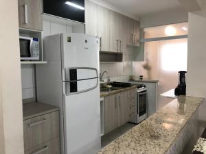 Una cocina con un refrigerador blanco y un fregadero. en Apartamento beira mar - Mongaguá, en Mongaguá