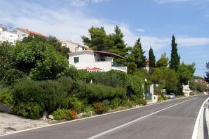a street with a white house on the side of a road at Apartments by the sea Seget Vranjica, Trogir - 7508 in Seget Vranjica