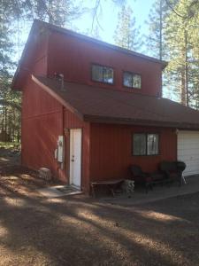 a red barn with a white door and two chairs at Cheerful 2-Bedroom Cottage Near Eagle Lake in Susanville