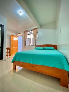 a bedroom with a bed with blue sheets and a window at La Terraza Hospedaje in Moyobamba
