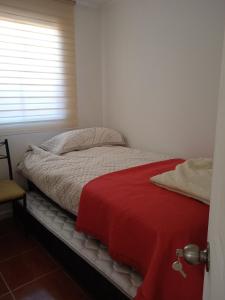 a bedroom with a bed with a red blanket at Hospedaje el Rosario in Angol