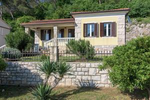 a house with a stone wall and a fence at Seaside holiday house Plomin Luka, Labin - 7466 in Plomin