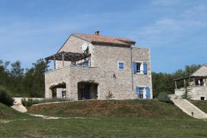 a large stone house on a hill with a grass field at Family friendly house with a swimming pool Skrapi, Central Istria - Sredisnja Istra - 7526 in Brajkovići