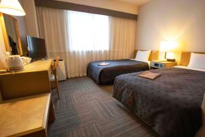 水戸市にあるコートホテル水戸のベッド2台、デスク、テレビが備わるホテルルームです。