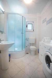 a bathroom with a shower toilet and a washing machine at Apartments by the sea Razanj, Rogoznica - 7484 in Ražanj
